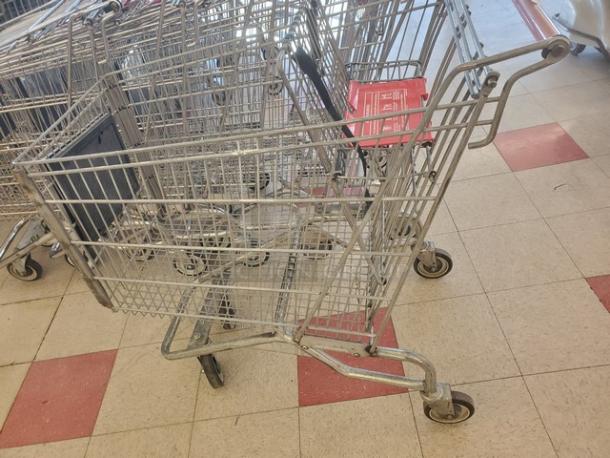 Lot of 5 metal shopping carts, standard size, silver finish, moderate wear. Ideal for retail use. Wheels and frames intact.