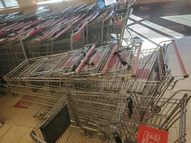 Lot of 5 metal shopping carts with red handles, nested together. Used condition, ideal for retail environments.