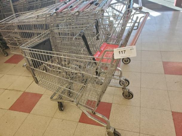 Set of 5 metal shopping carts in good condition, with swivel wheels and red handles. Tag marked "117" and quantity "5".