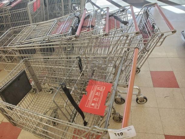 Lot of 5 metal shopping carts with red handles, used condition. Tag reading "119" indicates lot number for auction.