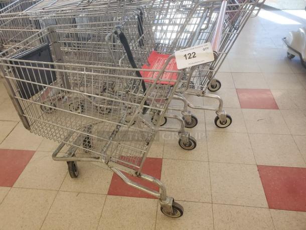 Lot of 5 metal shopping carts in used condition, nested together, with red seat backs and wheels, item number 122 visible.
