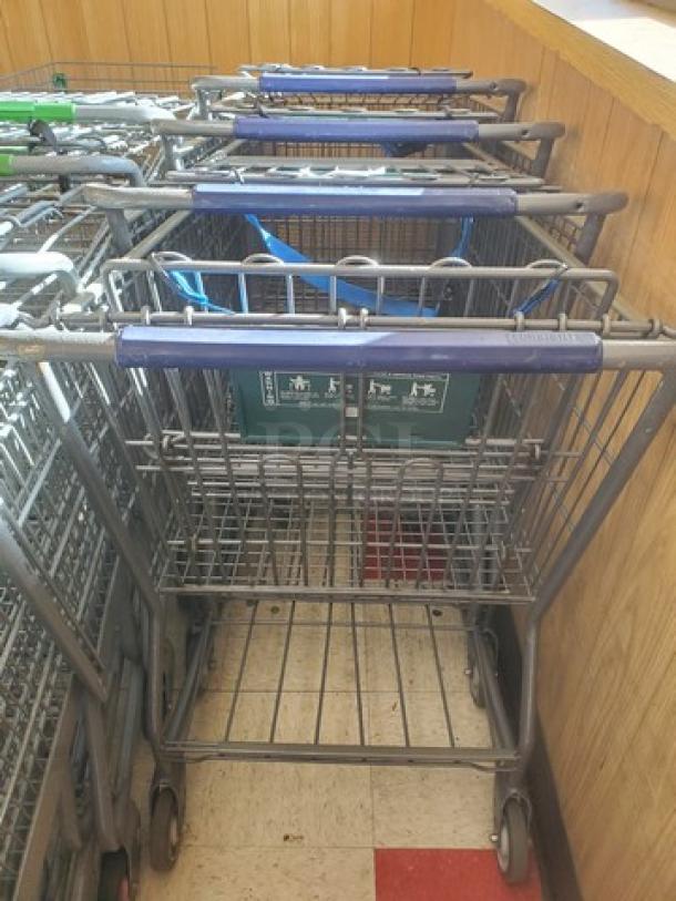 Lot of 4 shopping carts with blue handles, metal construction, moderate wear. No visible brand or model markings.