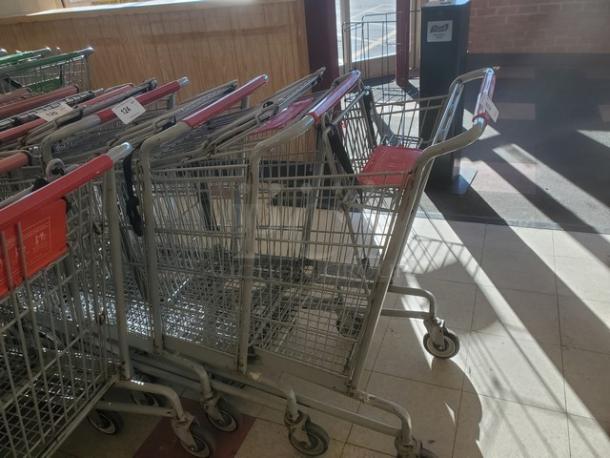 Lot of 5 metal shopping carts with red handles, in used condition. Tags on handles indicate item number and auction details.