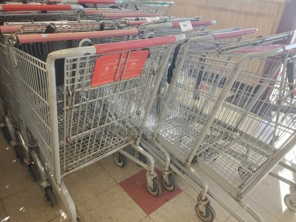 Lot of 5 metal shopping carts with red handles, used condition, includes signage.