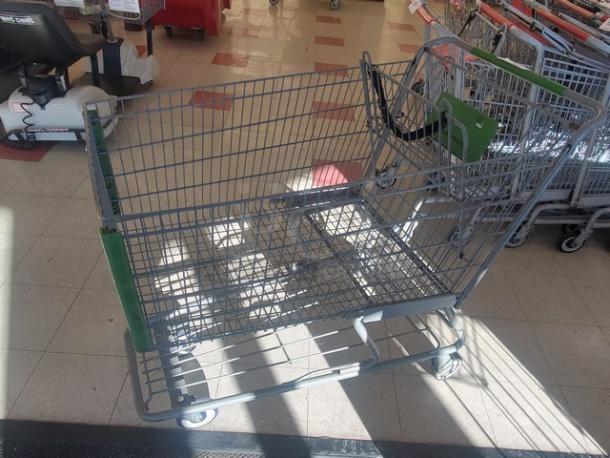 Lot of 4 shopping carts with green handles. Sturdy wire frame, good condition, swiveling wheels. Ideal for retail use.