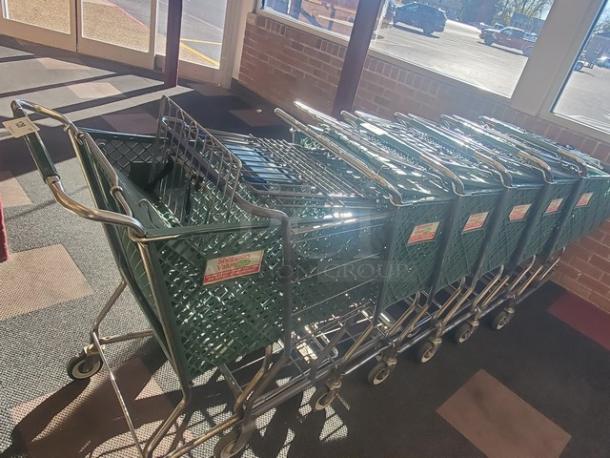 Lot of 4 green shopping carts in good condition, stackable design, metal frames, with labels indicating use for stores.