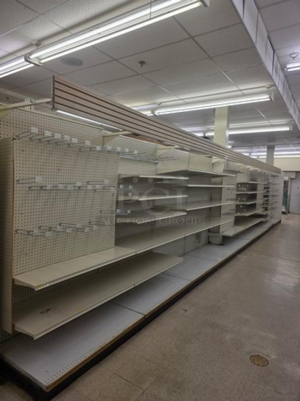 Single sided gondola shelving, 40 feet long, featuring multiple adjustable shelves. Used condition with metal perforations.