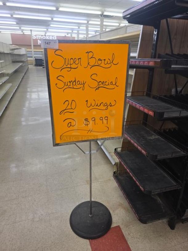 Bright orange "Super Bowl Sunday Special" sign advertises 20 wings for $9.99, mounted on a metal stand.