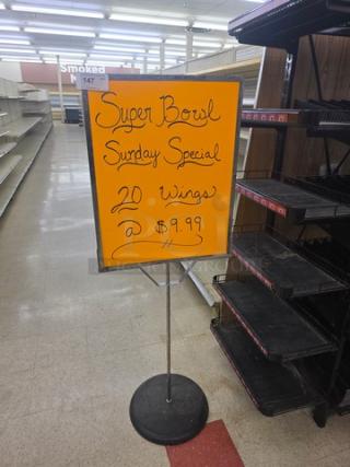 Bright orange "Super Bowl Sunday Special" sign advertises 20 wings for $9.99, mounted on a metal stand.