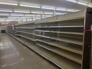 Double sided gondola shelving, 63' length, metal, beige color, multi-tier; used condition, in a retail setting.