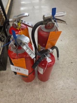 Lot of 4 red fire extinguishers with labels indicating inspection details and quantity tag reading "153."