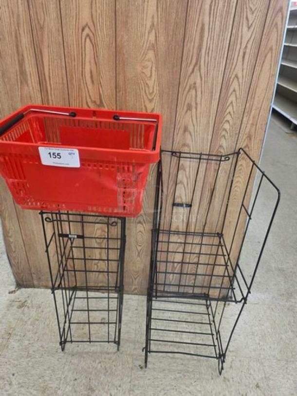 Lot of 3 miscellaneous items includes red plastic basket on metal rack and two black wire display racks. Item labeled "155".