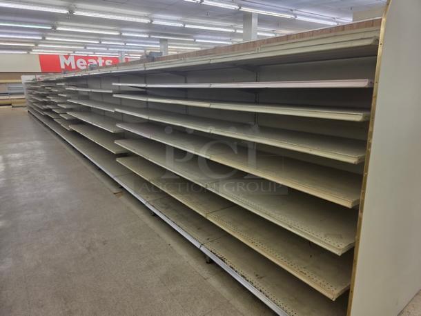 Single-sided gondola shelving, 63-feet long, features multiple adjustable metal shelves, fair condition. Buyer must remove.