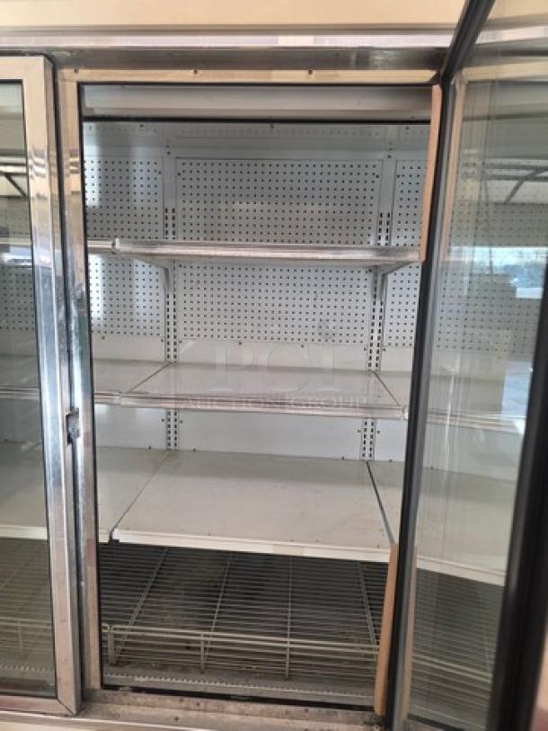 Kysor Warren three glass door freezer with metal shelving, reflective glass doors, and a stainless steel frame. Slight wear visible.