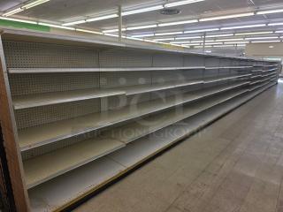 Double-sided gondola shelving, 65 feet long, white pegboard backing, multi-tiered, used condition, buyer must remove.