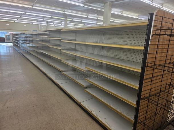 Double-sided gondola shelving, 65 feet, with multiple adjustable shelves. Good condition, pegboard backing, buyer must remove.