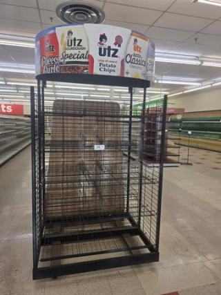 Black wire shelving unit with multiple tiers, Utz snack branding on top; slightly worn, ideal for retail display.
