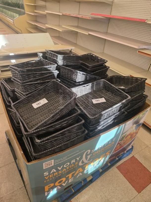 Lot of 50 black produce baskets stacked together, used condition, various tags with numbers for identification.