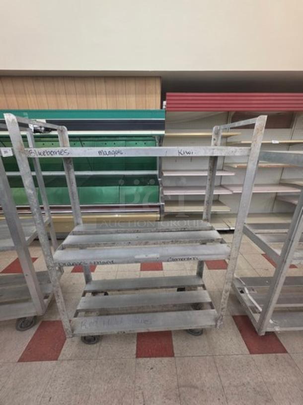 Aluminum mobile shelf cart with three tiers, caster wheels, and labeled sections. Used condition with visible wear.