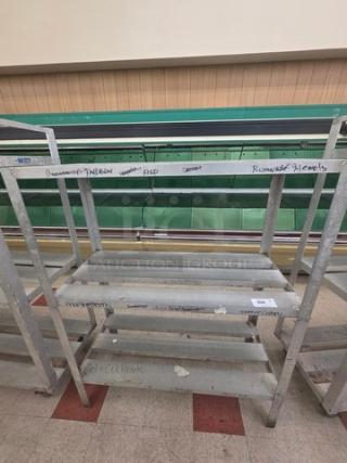 Aluminum shelf cart with multiple levels, used condition. Visible handwritten markings on shelves. Sturdy and functional.
