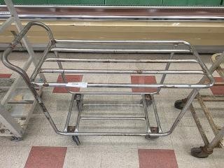 Mobile laundry cart base, metal frame, rusted condition, four caster wheels, rectangular structure.