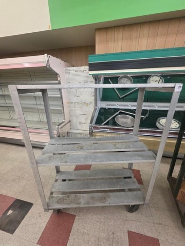 Aluminum mobile shelf cart with two slatted shelves, sturdy frame, and four wheels for easy movement. Used condition.