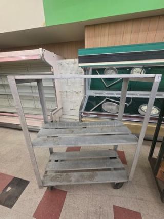 Aluminum mobile shelf cart with two slatted shelves, sturdy frame, and four wheels for easy movement. Used condition.