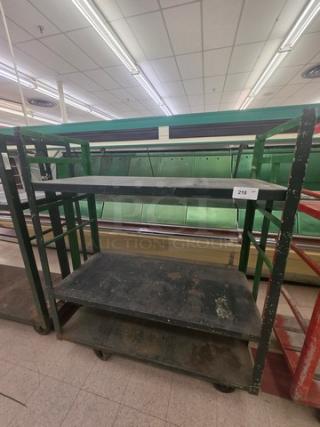 Industrial shelf cart with three metal shelves, worn green frame, and caster wheels. Label reads "218." Used condition.
