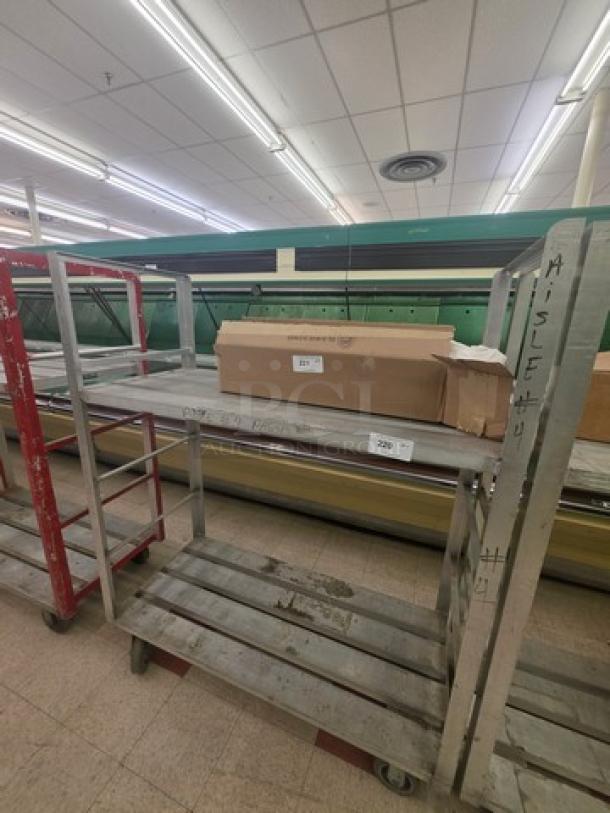 Aluminum mobile shelf cart with multiple shelves, wheels, and labeled "AISLE 4." Sturdy design, used condition.