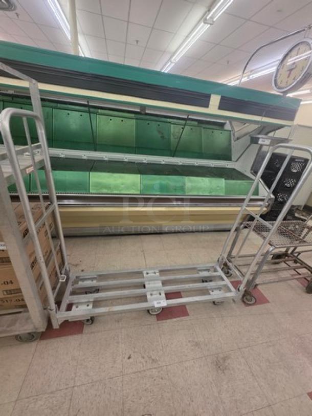 Aluminum mobile cart with a sturdy frame, swivel casters, and open shelves. Used condition, ideal for transport and storage.