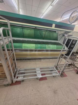 Aluminum mobile cart with a sturdy frame, swivel casters, and open shelves. Used condition, ideal for transport and storage.