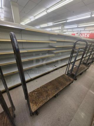 Industrial stock cart with metal frame and wooden platform. Shows wear and rust. Used for store inventory transport.