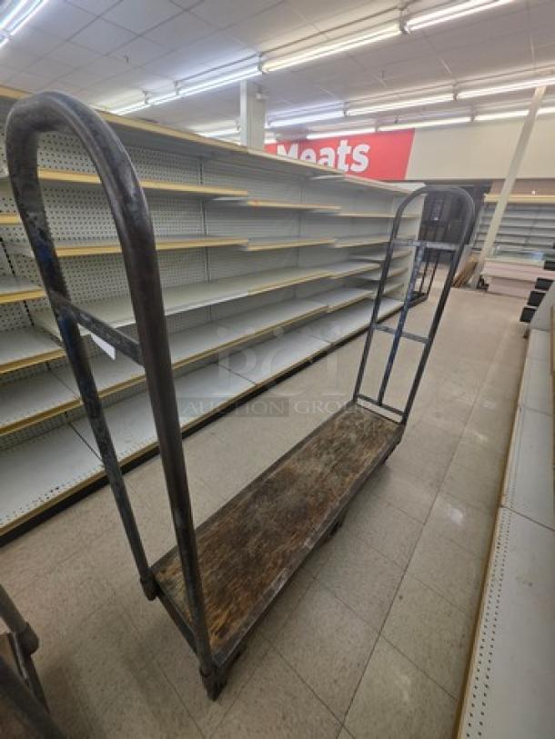 Heavy-duty metal stock cart with wooden platform. Used condition with visible wear. Ideal for warehouse or retail use.