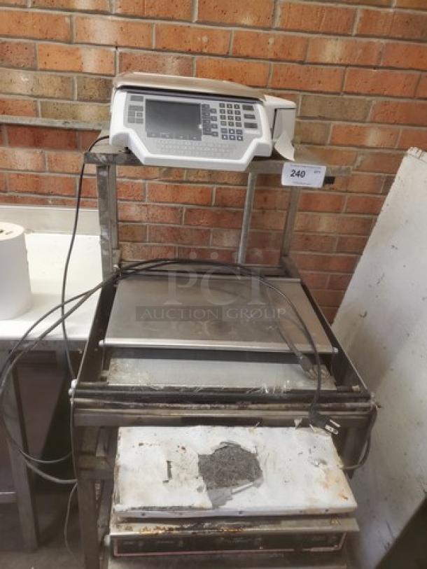 Commercial hand wrap station with integrated digital scale, keypad, and display. Worn metal surface, visible wires, and rust spots.