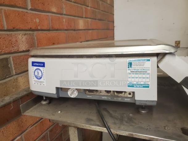 Commercial hand wrap station with metal top, visible approval label, showing ports and cables, used condition.