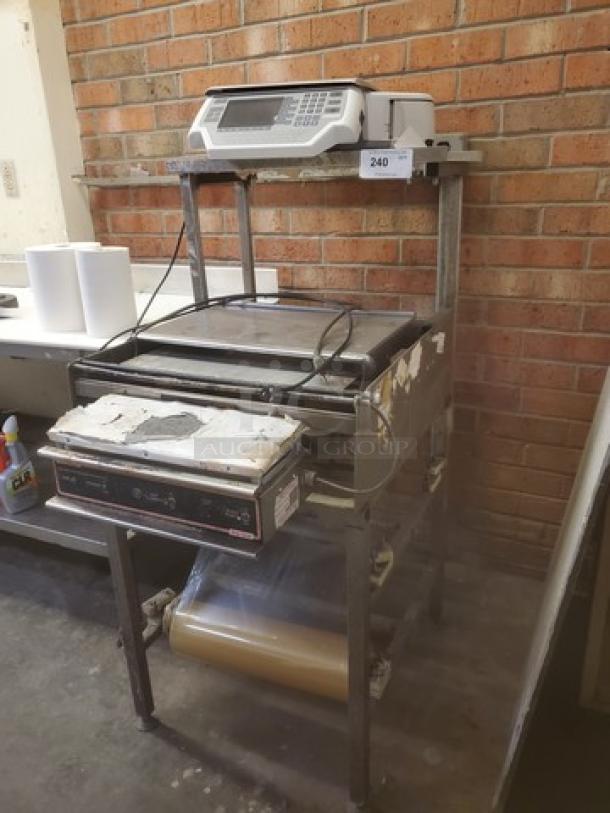Commercial hand wrap station with electronic scale and heat sealer. Includes film roll holder. Used condition, minor wear visible.