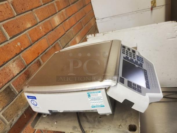 Commercial hand wrap station with stainless steel surface and digital keypad. Features visible brand label and usage instructions.