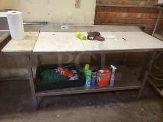Stainless steel cutting board butcher block table with a lower shelf, showing signs of use. No contents included.