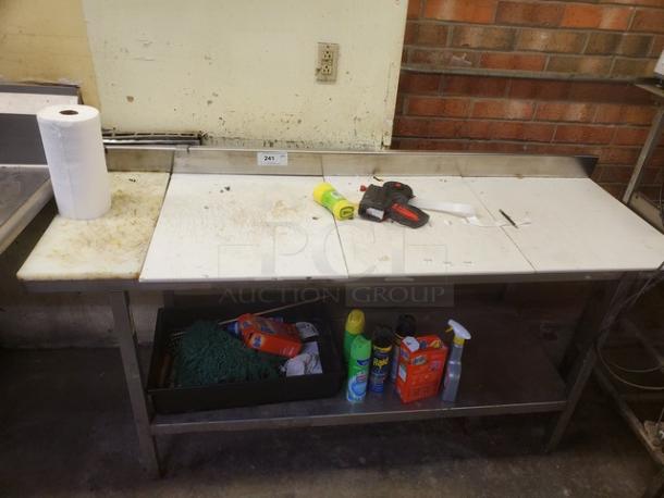 Stainless steel cutting board butcher block table with integrated backsplash, showing wear. Items on and under table not included.