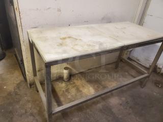 Stainless steel cutting board butcher block table with dual white surfaces, signs of wear and use, ideal for heavy-duty kitchen tasks.