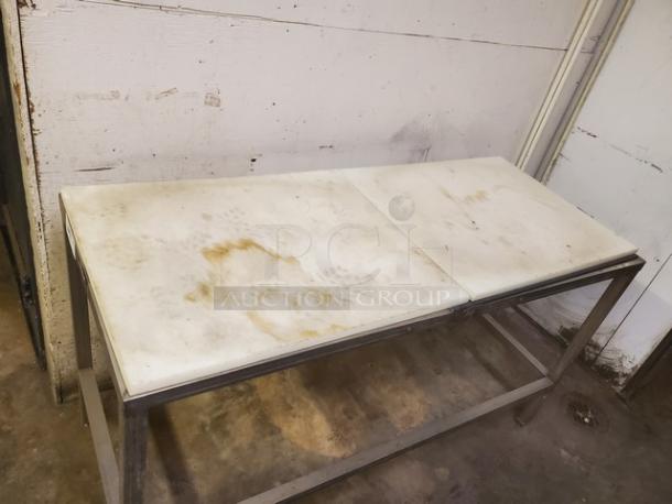Stainless steel cutting board butcher block table with worn white surface. Signs of use and stains visible.