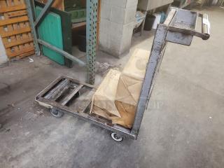 Sturdy retail dolly cart with steel frame and four wheels, carrying cardboard boxes. Ideal for warehouse transport. Good condition.