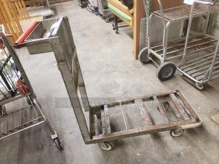 Metal retail dolly cart with a handle, four wheels, and a flat base. Used condition, visible wear and rust on frame.