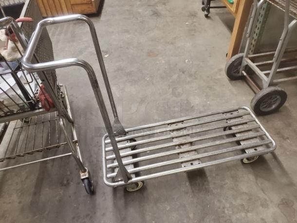 Metal retail dolly cart with slatted base, sturdy handle, and four wheels for maneuverability. Good condition, suitable for heavy loads.