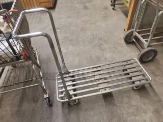 Metal retail dolly cart with slatted base, sturdy handle, and four wheels for maneuverability. Good condition, suitable for heavy loads.