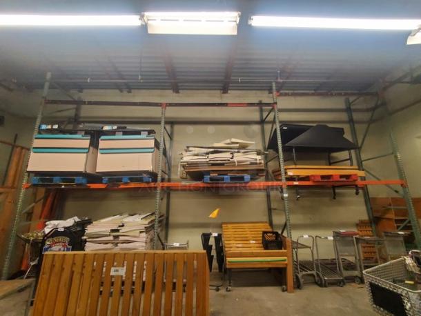 Large metal pallet rack; three levels; used condition; contents not included; industrial warehouse setting.