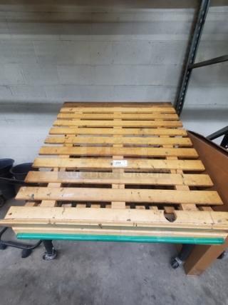 Wood pallet roller with metal frame and wheels, used condition. Tag number 254 visible on the surface.