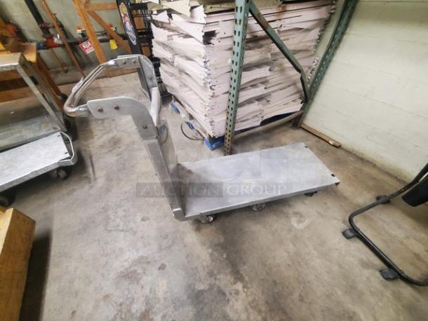 Stainless steel utility cart with handle, large platform, and swivel casters. Used condition, industrial design, sturdy construction.