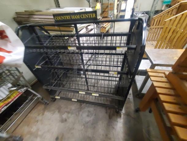 Black metal wire display rack with multiple shelves, labeled "Country Ham Center," on wheels for mobility, used condition.
