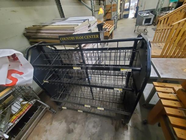 Metal wire display rack labeled "Country Ham Center" with three shelves, used condition, black frame, wheels for mobility.